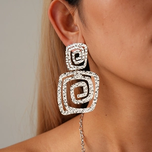 Nahaufnahme eines Models mit großen silbernen quadratischen Spiralohrringen mit Hammerschlag