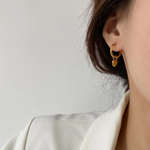 Minimalist gold heart dangle hoop earrings worn by a model in a stylish side view profile