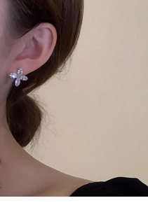Close-up of a silver butterfly earring with sparkling cubic zirconia on a model's ear
