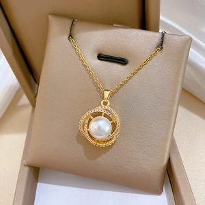 Close-up of bird nest necklace featuring white pearl and zircon inlay in a gold finish