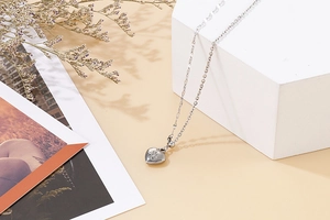 Detail of silver heart pendant with starburst engraving on minimalist link chain