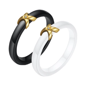 Ceramic rings in black and white with gold X-shape crossover and zircon inlay