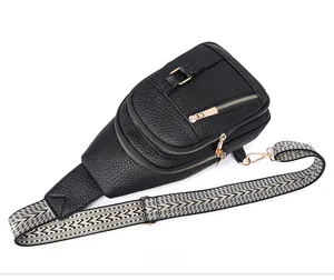 Detailed view of black pebbled leather chest bag with a wide geometric fabric strap