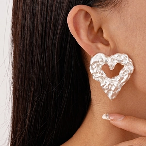 Detail of large silver heart stud earring with liquid lava texture on female model