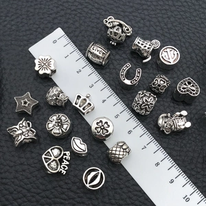 Detailed assortment of silver alloy spacer beads and charms with scale measurement on black leather