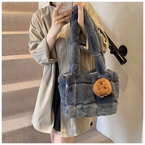 Detail of blue-grey plush underarm bag featuring quilted texture and cute bear charm