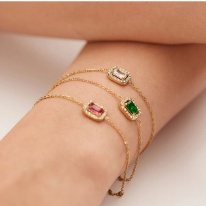 Detailed view of three gold-plated bracelets featuring white, green, and red zircon stones