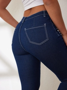 Detail of high-waisted skinny jeans in dark blue with contrast white stitching and pockets