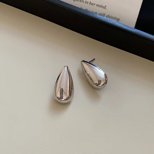 Macro view of polished silver water drop earrings with a metallic high-shine finish
