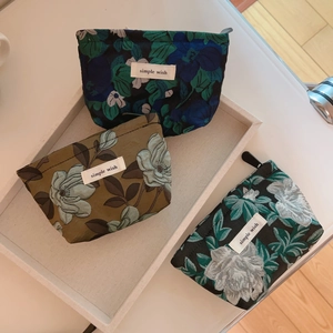 Three-piece floral jacquard mini storage pouches with zipper closure on a grey tray
