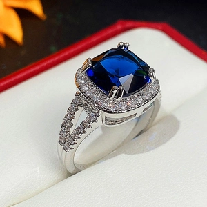 Macro view of a square blue gemstone ring with sparkling diamonds on a silver band
