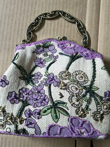 Close-up of vintage beaded floral embroidery and ornate bronze metal handle on linen bag