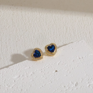 Close-up of heart-shaped blue zircon earrings with a gold frame and white crystal halo