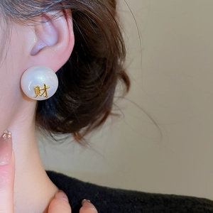 Détail d'une boucle d'oreille perle blanche avec caractère chinois doré sur mannequin