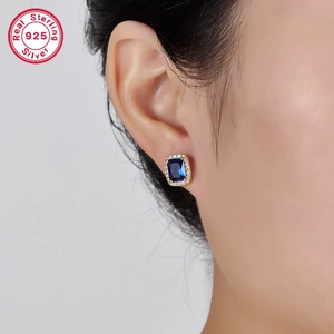 Macro view of S925 sterling silver square blue gemstone earrings worn on ear
