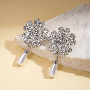 Detail of silver clover earrings with sparkling rhinestones and teardrop pearl drops