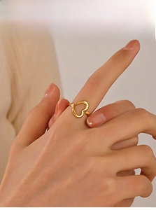 Detail of a minimalist gold hollow heart-shaped open ring worn on a finger
