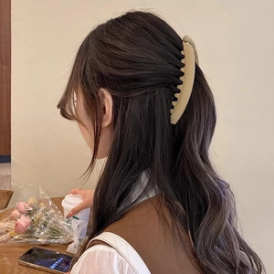 Detail of 13cm matte cream banana clip holding wavy brown hair in a café setting