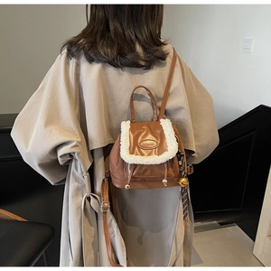 Brown leather backpack with white faux fur trim and drawstrings shown on a model