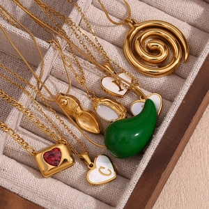Detail of assorted gold-plated necklaces with enamel heart and letter pendants in a jewelry box