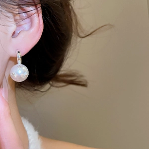 Close-up of elegant C-shaped silver pearl earrings with star-set zircon on model