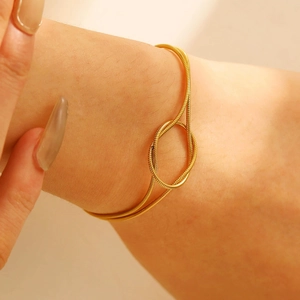 Close-up of golden stainless steel snake chain bracelet with a minimalist knot detail