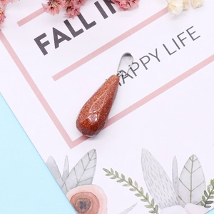 Macro shot of faceted teardrop goldstone pendant with silver metal clasp on decorative card