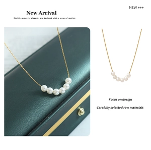 Detail of five white pearls arranged on a gold-plated titanium steel necklace chain