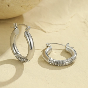 Elegant silver hoop earrings with sparkling white crystals on a stone pedestal