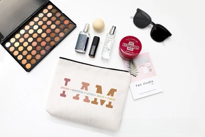 Flat lay of letter print makeup bag with cosmetics on white minimalist background
