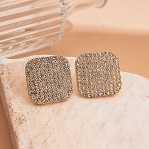 Elegant gold square stud earrings with pave crystals on a minimalist stone background