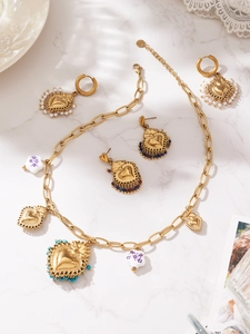 Mise à plat de collier vintage doré en cœur avec perles et breloques céramique sur marbre