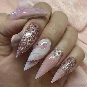 Pink marble stiletto press-on nails with glitter and rhinestones on light fabric