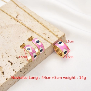 Detail showing pink enamel evil eye necklace and hoop earrings set on stone surface