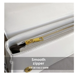 Detailed close-up of smooth gold metal zipper and white leather bag interior lining