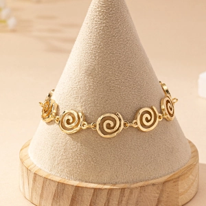 Detail of gold spiral link bracelet showcased on a wooden jewelry display stand