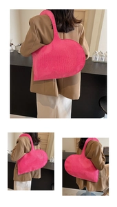 Detail of a large magenta heart-shaped shoulder bag with luxury crocodile texture