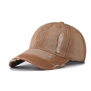 Detailed macro view of distressed brown denim baseball cap with vintage frayed holes