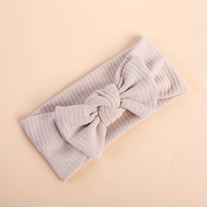 Detail view of beige ribbed knit baby headband featuring a soft elastic bow design