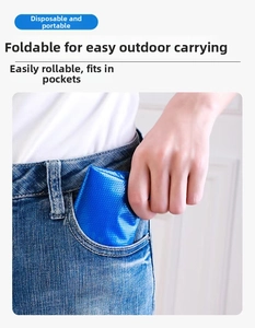 Blue foldable waterproof shoe cover being placed into a jeans pocket for easy portability