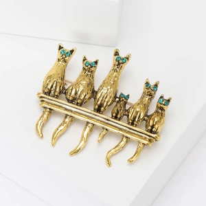Vintage gold cat brooch with six green-eyed kittens sitting on a metal bar accessory