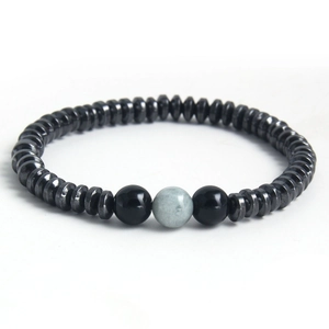 Minimalist matte black stone beaded bracelet featuring a unique grey-green centerpiece bead