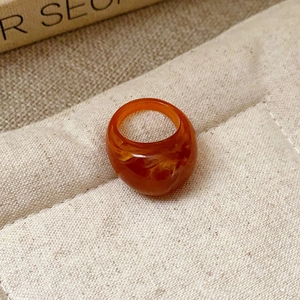 Macro shot of an amber resin ring with marble texture on a beige fabric display stand