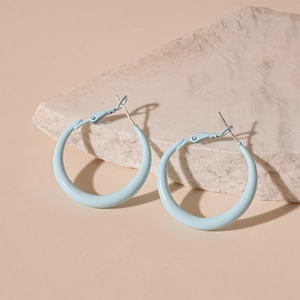 Close-up of light blue hoop earrings on a textured stone for a minimalist look