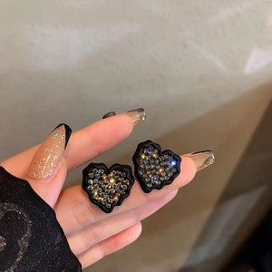 Détail de boucles d'oreilles en cœur avec bords noirs mats et diamants brillants