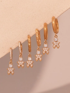 Macro detail of six gold earrings set with zircon studs and cute human-shaped pendants