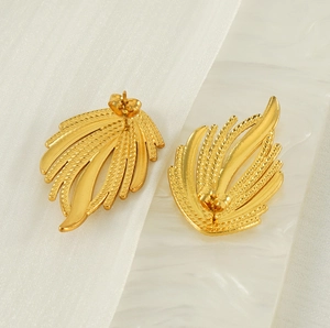 Close-up of 18K gold plated woven texture earrings on white marble tray and silk