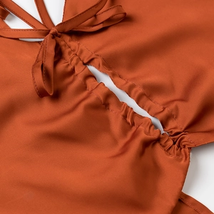 Macro détail du haut en satin auburn avec nœud à nouer et design ajouré à fronces