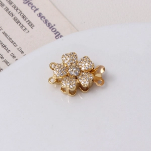 Detail of gold flower jewelry clasp with white cubic zirconia and side link rings