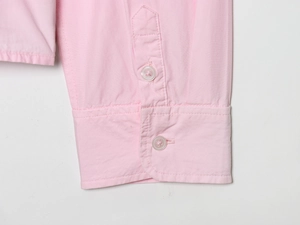 Detail of pink cotton shirt cuff showing delicate fabric texture and button closure
